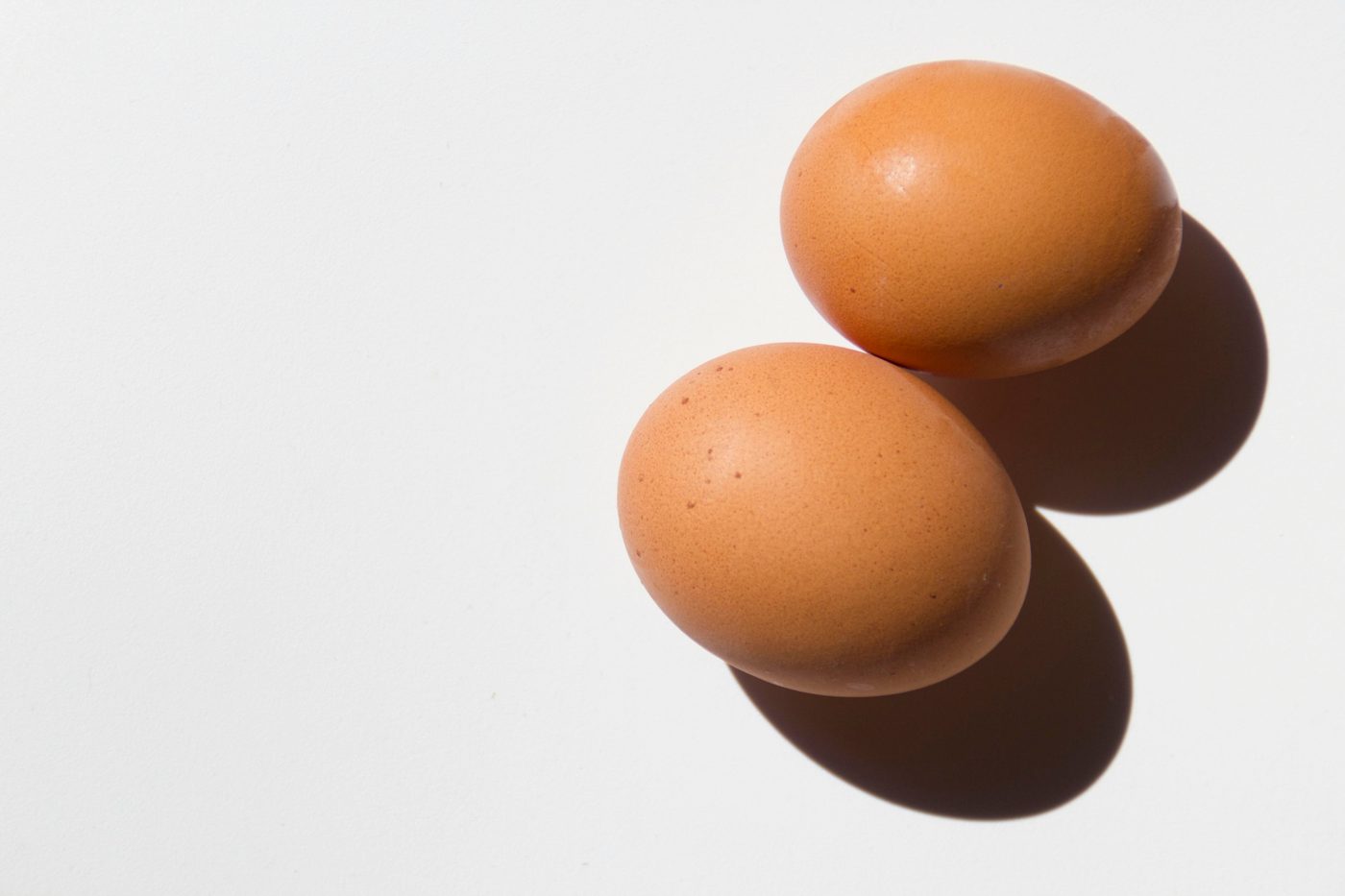 Two brown eggs on a white surface